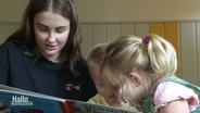 Eine junge Frau liest Kindern aus einem Buch vor. © Screenshot 