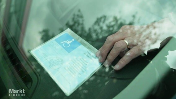 Ein Behindertenausweis wird vorne in ein Auto gelegt. © Screenshot 
