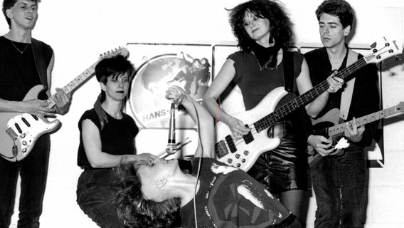 Eine alte Aufnahme zeigt eine Punkband auf der Bühne. Eine alte Aufnahme zeigt eine Punkband auf der Bühne. © Screenshot