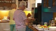 Zwei Urlauber stehen an einem Buffet. © Screenshot 