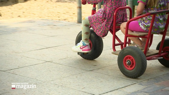 Zwei Kinder fahren mit einem Dreirad. © Screenshot 