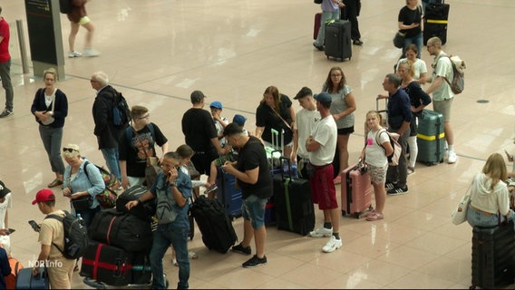 Eine lange Schlange hat sich am Flughafen gebildet. © Screenshot 