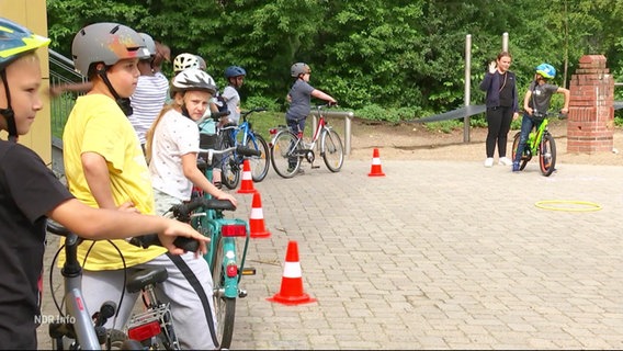 Mehrere Kinder mit Fahrrädern warten in einer Schlange. © Screenshot 