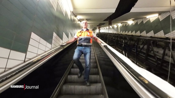 Person mit Warnweste geht eine Rolltreppe hinab © Screenshot 