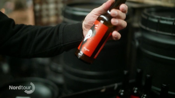 Eine Bierflasche in der Hand. © Screenshot 