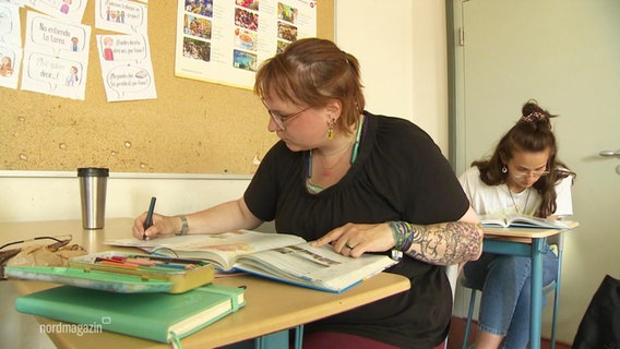 Eine Frau arbeitet in einem Klassenzimmer. © Screenshot 