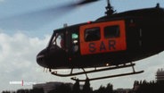 Ein Hubschrauber der Luftrettung. Er ist komplett schwarz, nur der Türbereich ist orange, darauf steht in dunklen Buchstaben "SAR". © Screenshot 