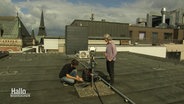 Zwei Personen arbeiten auf einem Dach an einem Gerät. © Screenshot 