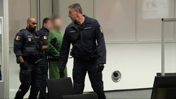 Der Angeklagte wird von Justizbeamten in den Gerichtssaal gebracht. © Screenshot 