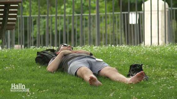 Ein Mann liegt während der Mittagshitze auf dem Rasen. © Screenshot 