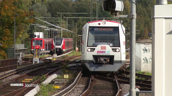 Die neue S-Bahn in weißem Design im Einsatz auf den Gleisen. Im HIntergrund links zwei rote S-Bahn-Züge. © Screenshot 