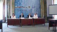 Mehrere Menschen sitzen auf einer Pressekonferenz © Screenshot 