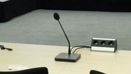Ein Mikrofon steht in einem Gerichtssaal. © Screenshot 