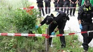 Polizisten durchsuchen ein Gebüsch. © Screenshot 