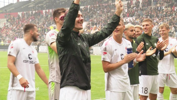 Spieler vom FC St. Pauli stehen jubelnd auf dem Rasen © Screenshot 