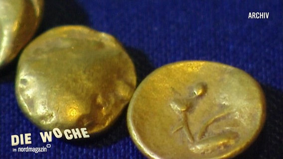 Nahaufnahme: Altertümliche Goldmünzen liegen auf einem blauem Stoffuntergrund. © Screenshot 