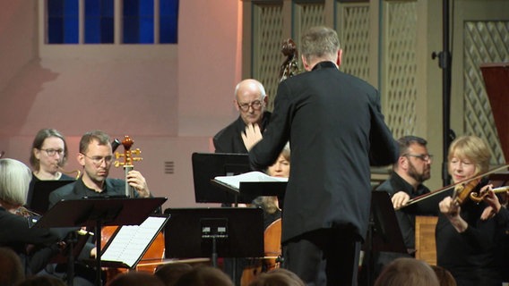 Dirigent und Mitglieder eines klassischen Ensembles. © Screenshot 