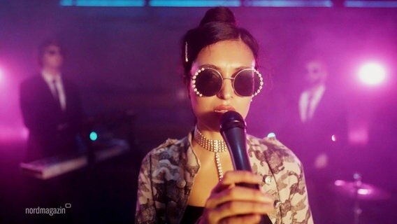 Carina Castillo trägt eine Sonnebrille und steht auf einer Bühne. © Screenshot 
