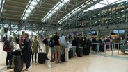 Eine lange Schlange von Urlaubern im Flughafen. © Screenshot 