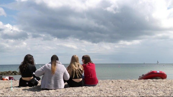 Vier Jugendliche sitzen am Ostseestrand und blicken aufs Meer. © Screenshot 