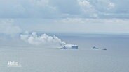Auf dem offenen Meer steigen große Rauchwolken von einem Frachter empor, daneben einige kleinere Schiffe. © Screenshot 