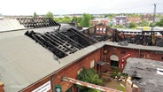 Blick auf das eingestürzte und zum Teil verkohlte Dach eines historischen bahnhofsgebäudes nach einem Brand. © Screenshot 