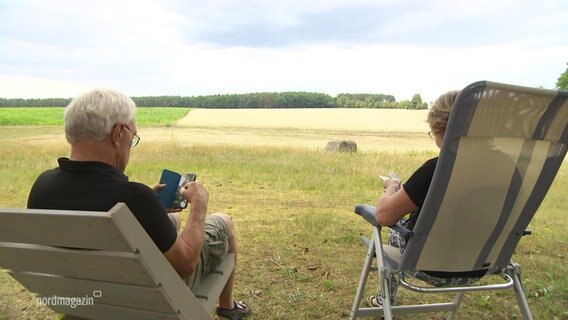Ein Mann und eine Frau sitzen in Campingstühlen vor einem Kornfeld. © Screenshot 