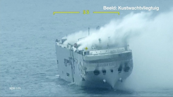 Blick auf einen Frachter auf offener See: Meterhohe Rauchwolken steigen vom Deck empor. © Screenshot 