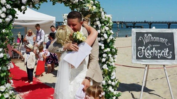 Ein Brautpaar küsst sich bei einer Strandhochzeit. © Screenshot 