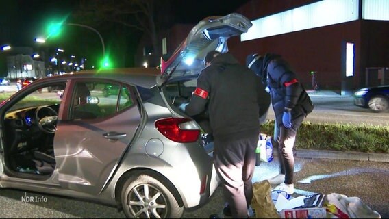 Bei Nacht durchsuchen Ermittler in Zivil den Kofferraum eines auf einer größeren Straße gestoppten Kleinwagens. © Screenshot 