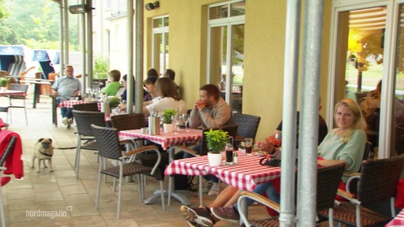 Leute sitzen und essen im Außenbereich eines Restaurants. © Screenshot 