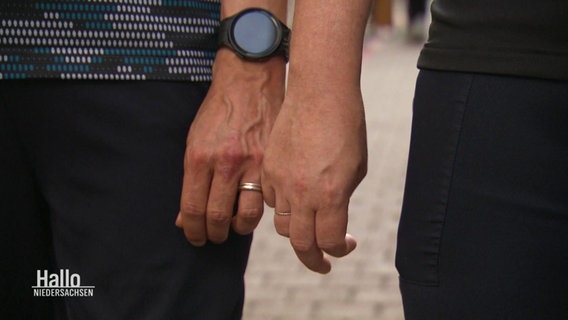 Zwei Männer beim Hände halten, sie tragen Eheringe. © Screenshot 