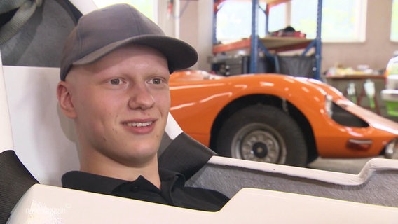 Der Rennfahrer Matti Pluschkell sitzt lächelnd in einem Auto. © Screenshot 