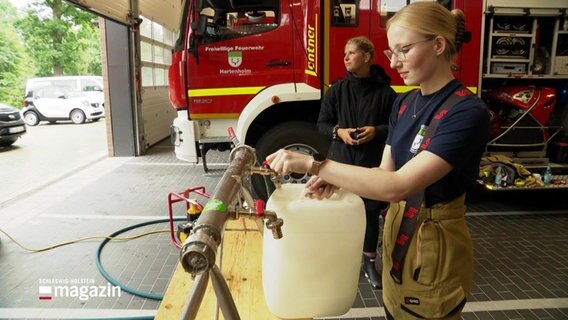 Eine junge Frau füllt in einer Feuerwache Wasser in einen Kanister. © Screenshot 