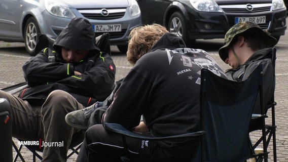Schlafende Wacken-Fans auf Campingstühlen auf einem Parkplatz. © Screenshot 