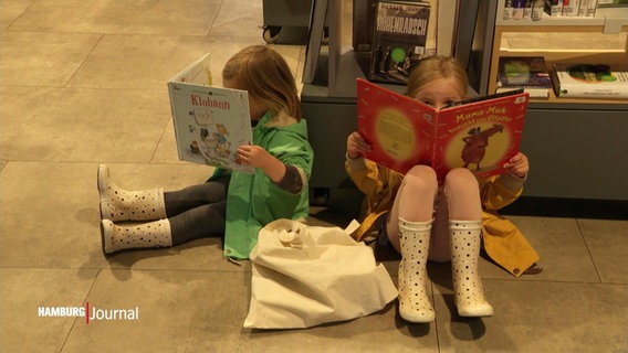 In den Bücherhallen: Kinder in Gummistiefeln sitzen auf dem Boden und schmökern in Büchern. © Screenshot 