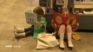 In den Bücherhallen: Kinder in Gummistiefeln sitzen auf dem Boden und schmökern in Büchern. © Screenshot 