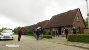 Menschen stehen vor einem Einfamilienhaus. © Screenshot 