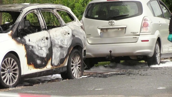 Zwei ausgebrannte Autos werden von der Polizei untersucht. © Screenshot 