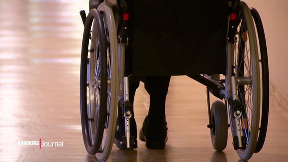 Ein Mensch in einem Rollstuhl auf einem leeren Gang. © Screenshot 