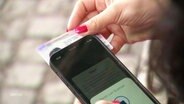 Jemand hält einen Personalausweis auf die Rückseite eines Smartphones. © Screenshot 