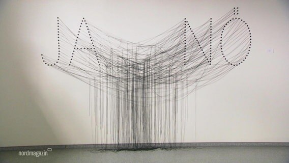 Kunstinstallation mit schwarzen Fäden an einer weißen Wand. DIe FÄden bilden die Wörter "Ja" und "Nö". © Screenshot 