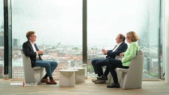 Personen in Stühlen vor einer Fensterfront. Sie sitzen sich gegenüber. © Screenshot 