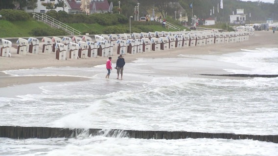 Menschen gehen an einem stürmischen Ostsee-Strand spazieren. © Screenshot 