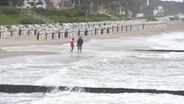 Menschen gehen an einem stürmischen Ostsee-Strand spazieren. © Screenshot 