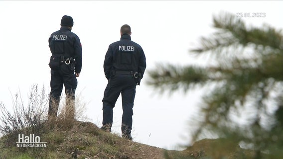 Zwei Polizisten stehen auf einer Anhöhe. © Screenshot 
