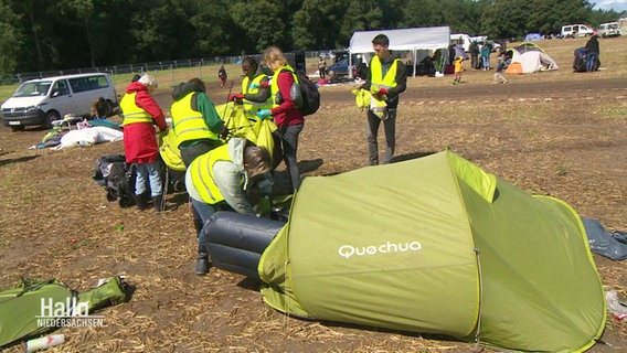 Menschen in gelben Westen durchsuchen ein Zelt. © Screenshot 
