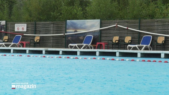 Ein Freibadbecken in dem Regentropfen auf die Wasseroberfläche schlagen. © Screenshot 