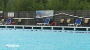 Ein Freibadbecken in dem Regentropfen auf die Wasseroberfläche schlagen. © Screenshot 