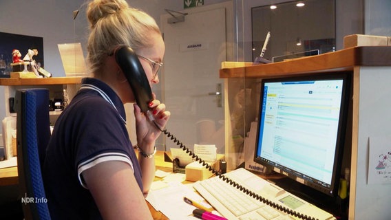 Eine Angestellte telefoniert an der Rezeption einer Arztpraxis © Screenshot 